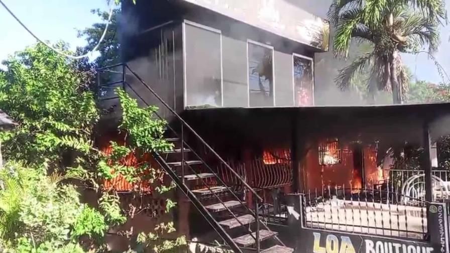 A building engulfed in flames with smoke billowing from windows and doors.