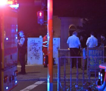 Vehículos de emergencia y personal de seguridad en una escena nocturna con luces de advertencia activadas.